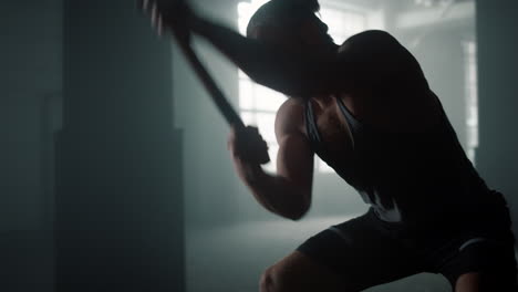 powerful athlete exercising with sledgehammer. man hitting tire with hammer