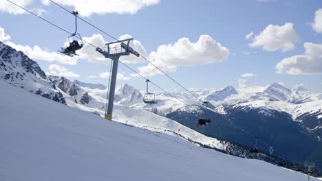 skiers ride ski lift with snowy mountain background, whistler, canada