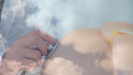 animation of clouds over caucasian doctor inspecting caucasian pregnant woman