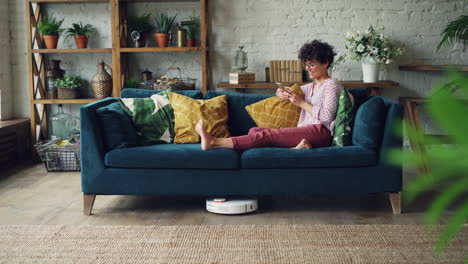 woman relaxing on sofa with robotic vacuum
