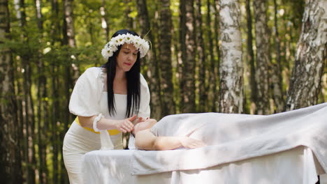 terapeuta mujer médico haciendo mujer relajante spa masaje facial con las manos al aire libre en el bosque