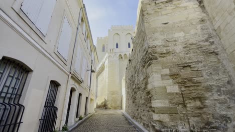 small beautiful alley in france made of old houses with light stone and fortress in the background made of historical stones