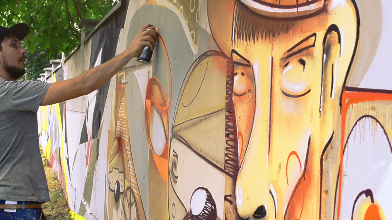 Kunstneren tegner graffiti på et hegn. Graffiti på et hegn