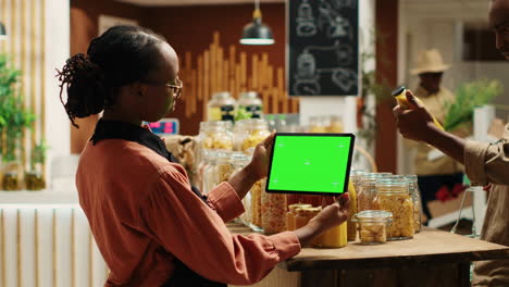 una mujer afroamericana usa una pantalla verde en una tableta en un supermercado.