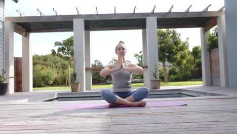 Mujer-Caucásica-Enfocada-Meditando-En-Una-Estera-De-Yoga-En-El-Jardín-En-Cámara-Lenta