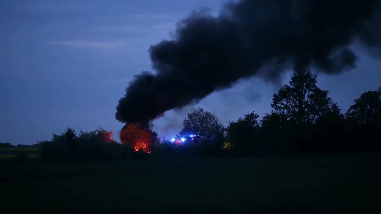 Flashing Beacons Of A Firetruck At The Location Of A Burning Field In Zlotoryja, Poland With Thick Black Smoke At Dawn - wide shot