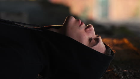 vertical portrait shot of handsome young man with fashion black hoodie looking aside at camera, cinematic and emotional