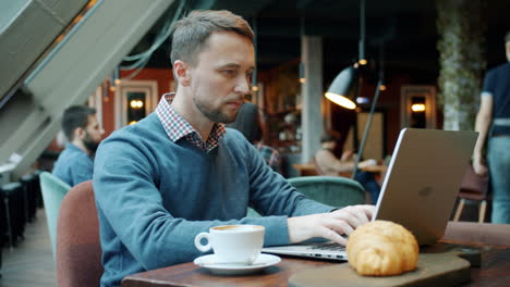man working on laptop in a cafe