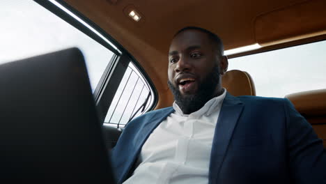 surprised african american man getting good news at luxury car.