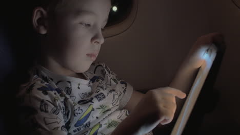 Boy-traveling-by-plane-and-playing-game-on-tablet-PC