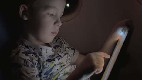 niño viajando en avión y jugando a un juego en una tableta