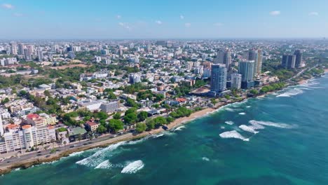 Aerial-panorama-shot-of-GEORGE-WASHIGTON-AVENUE-and-cityscape-of-Santo-Domingo-with-blue-ocean-in-summer