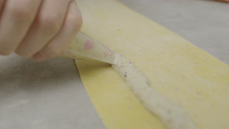 layering down white mushroom sauce onto lasagna dough