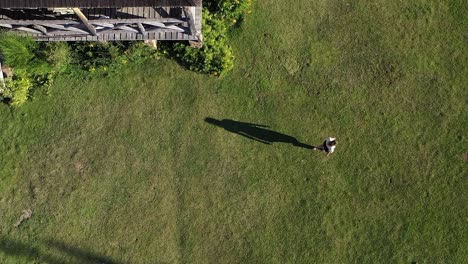 Junge-Frau,-Die-In-Einem-Großen-Hausgarten-Bei-Sonnenuntergang-Aus-Der-Vogelperspektive-Spazieren-Geht,-Aufgenommen-In-Zeitlupe-60fps