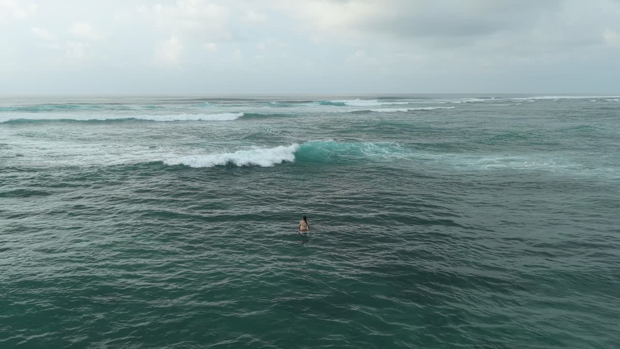 Lone surfer waiting for a wave on bali's pandawa beach