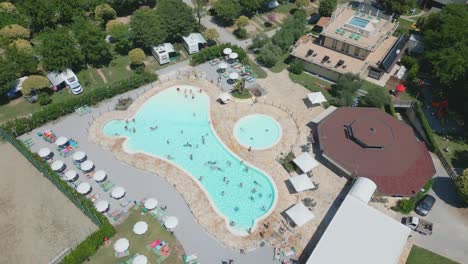 Vista-Aérea-De-Personas-Nadando-En-La-Piscina-En-El-Camping-Baia-Verde-En-El-Lago-De-Garda,-Italia