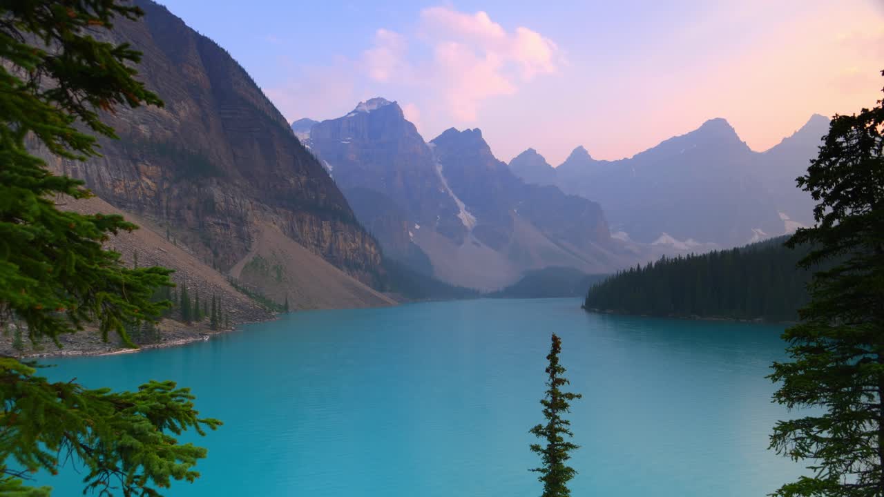 Timelapse of Lake Louise at sunset, with turquoise waters reflecting snow-capped peaks. A cinematic sweep of Banff’s alpine beauty, framed by forest silhouettes and glowing mountain skies