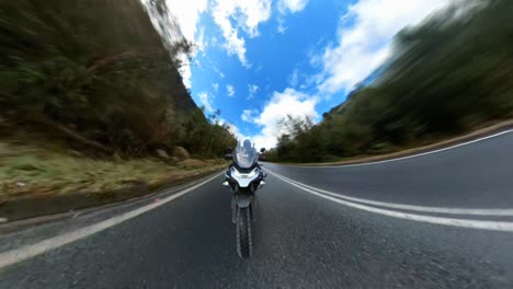 hiperlapso de una motocicleta montada en una carretera rural pavimentada rodeada de bosque nativo en un hermoso día soleado