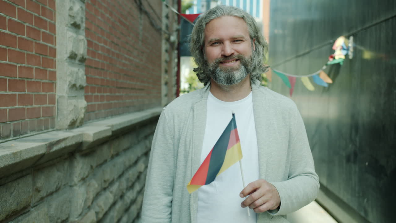 Smiling Man Holding German Flag in City Alley
