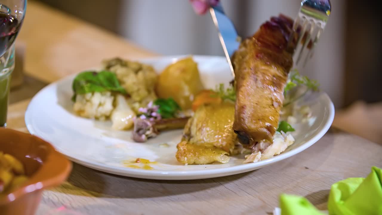 primer plano de las manos de un hombre cortando un trozo de carne de una costilla de cerdo en una cena en un restaurante