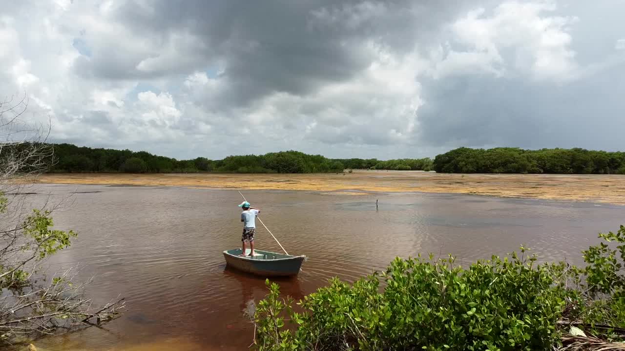 niño remando en un pequeño bote de pesca en un lago marrón al mediodía