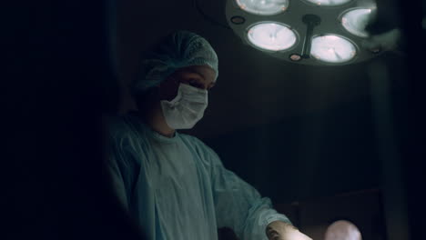 retrato de un médico realizando una operación quirúrgica en la sala de emergencias de un hospital oscuro.