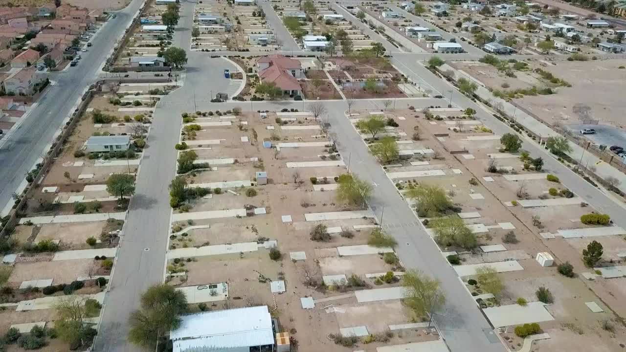 sobrevuelo aéreo de un parque de casas móviles parcialmente abandonado en una ciudad desierta, desplazamiento