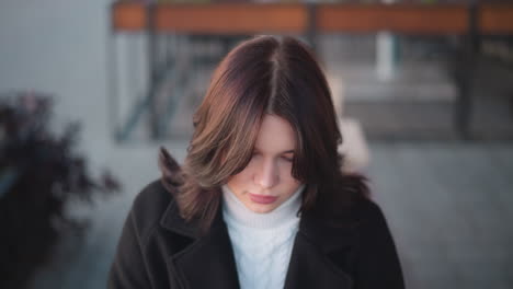 lady seated with focused expression, something in front of her, wind gently swaying her hair in outdoor setting, soft lighting, blurred background