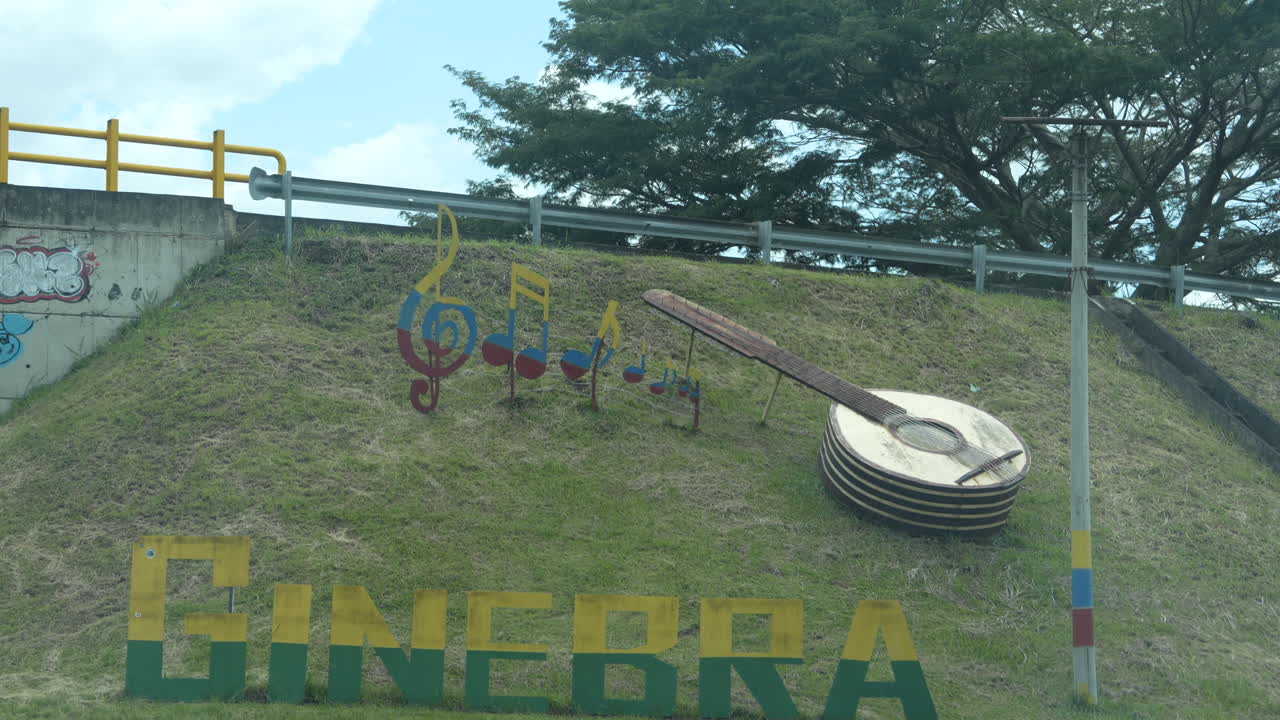 Una vibrante escultura con temática musical decora una ladera cubierta de hierba en Ginebra, Valle. Un cielo brillante y despejado realza este punto de referencia al borde de la carretera, capturando la esencia artística de la zona