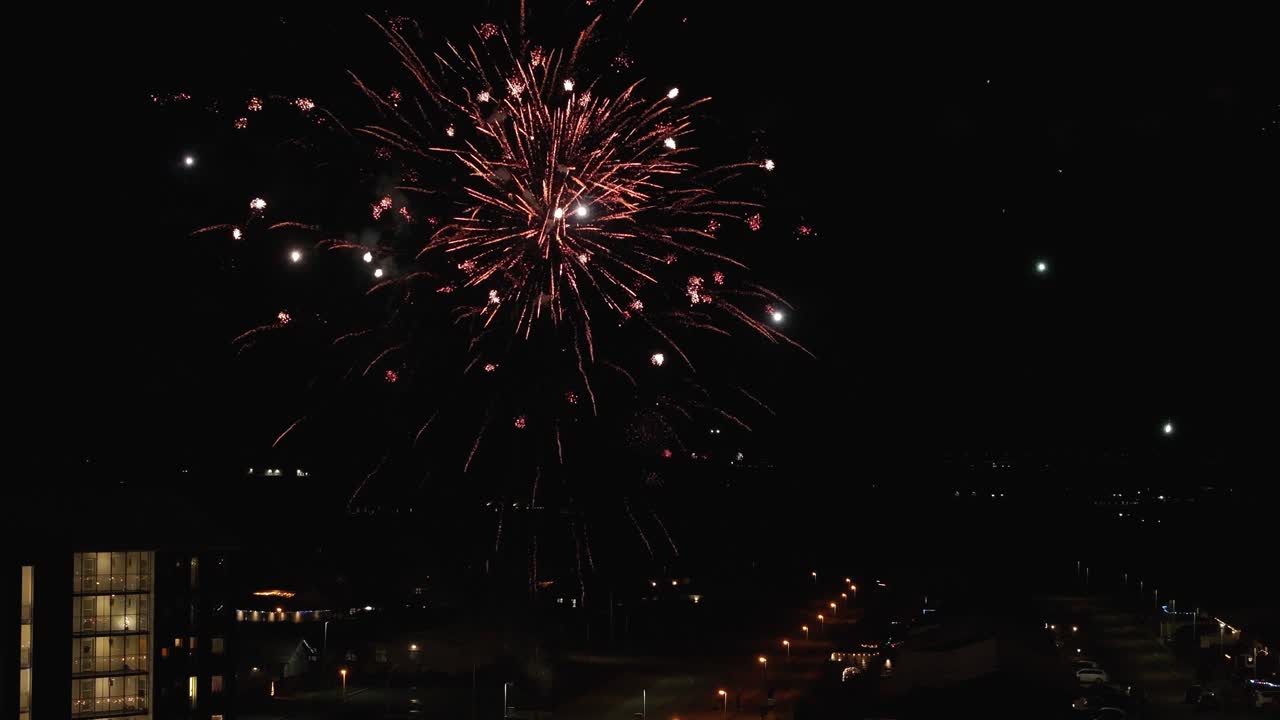 Exploding firework rockets at night sky of american town. Aerial wide shot. New years celebration in USA. Static shot. Colored splash and sparks