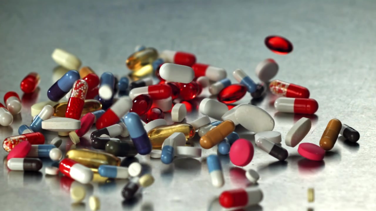 Colorful Pills and Capsules Falling in Slow Motion onto a Metallic Surface
