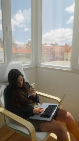 woman working remotely at home with laptop and smartphone