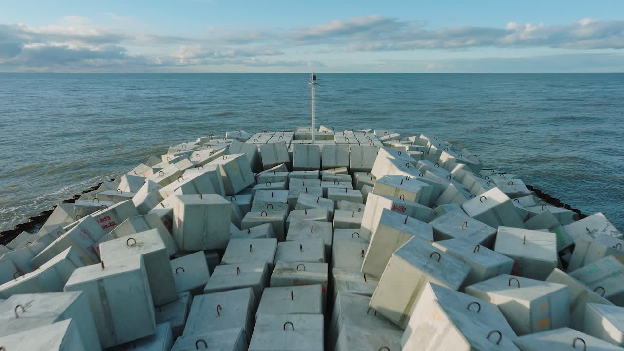 라트비아 리파자(liepaja)에 있는 발트해 연안에 콘크리트 블록과 바위가 있는 보호용 돌 부두의 공중 설정 전망, 해안 침식에 대한 해변 강화, 드론 샷이 뒤로 이동