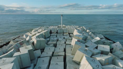 aerial establishing view of protective stone pier with concrete blocks and rocks at baltic sea coastline at liepaja, latvia, strengthening beach against coastal erosion, drone shot moving back low