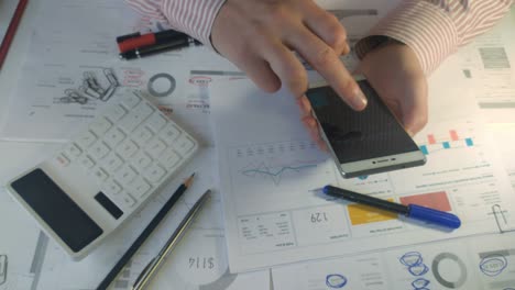 close hands of a businessman in the office holding the phone and counting the company's profits