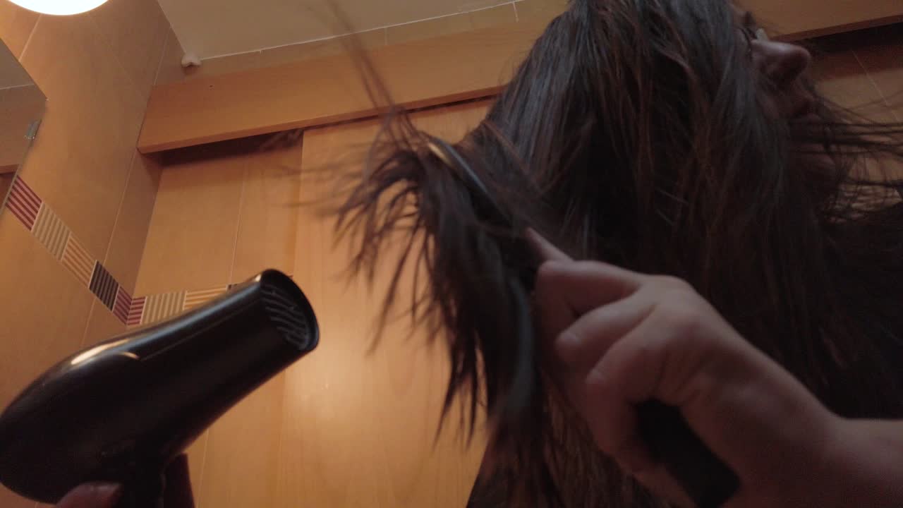 Woman drying straight brown hair with blowdryer, Slowmo Low Angle Close Up