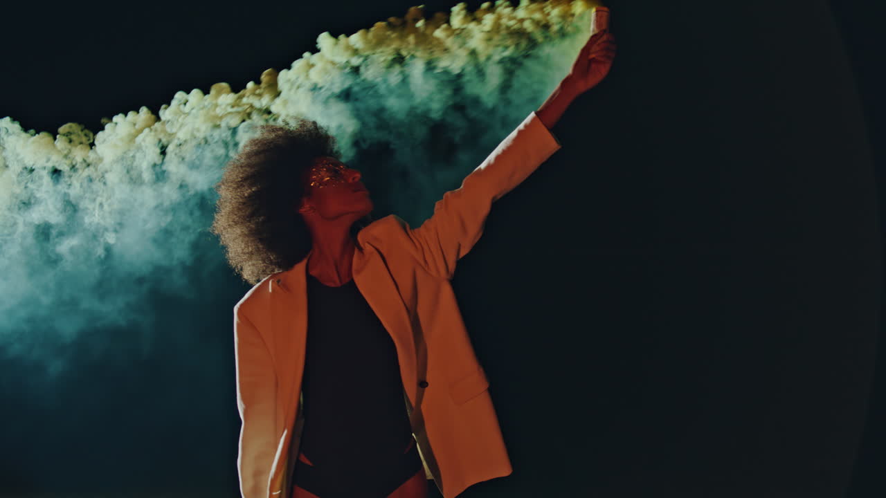 Attractive woman holding bomb with colorful smoke in black background alone.