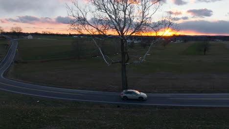 Aerial-rising-shot-of-cars-driving-on-windy-country-road-in-rural-America