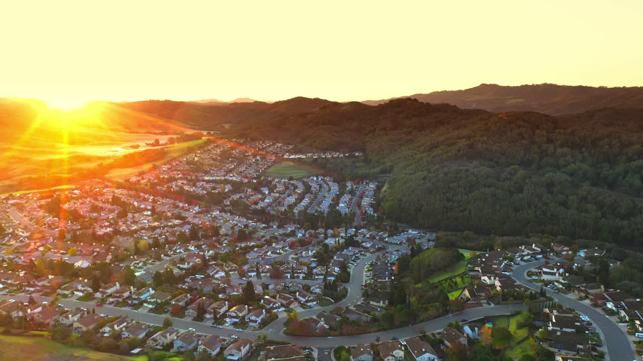 Sunrise in a beautiful suburban neighborhood with tract homes and green hills.