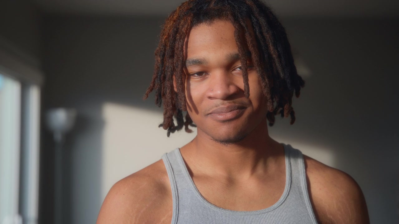 カメラを見つめるドレッドヘアの笑顔の若い男性のポートレート。