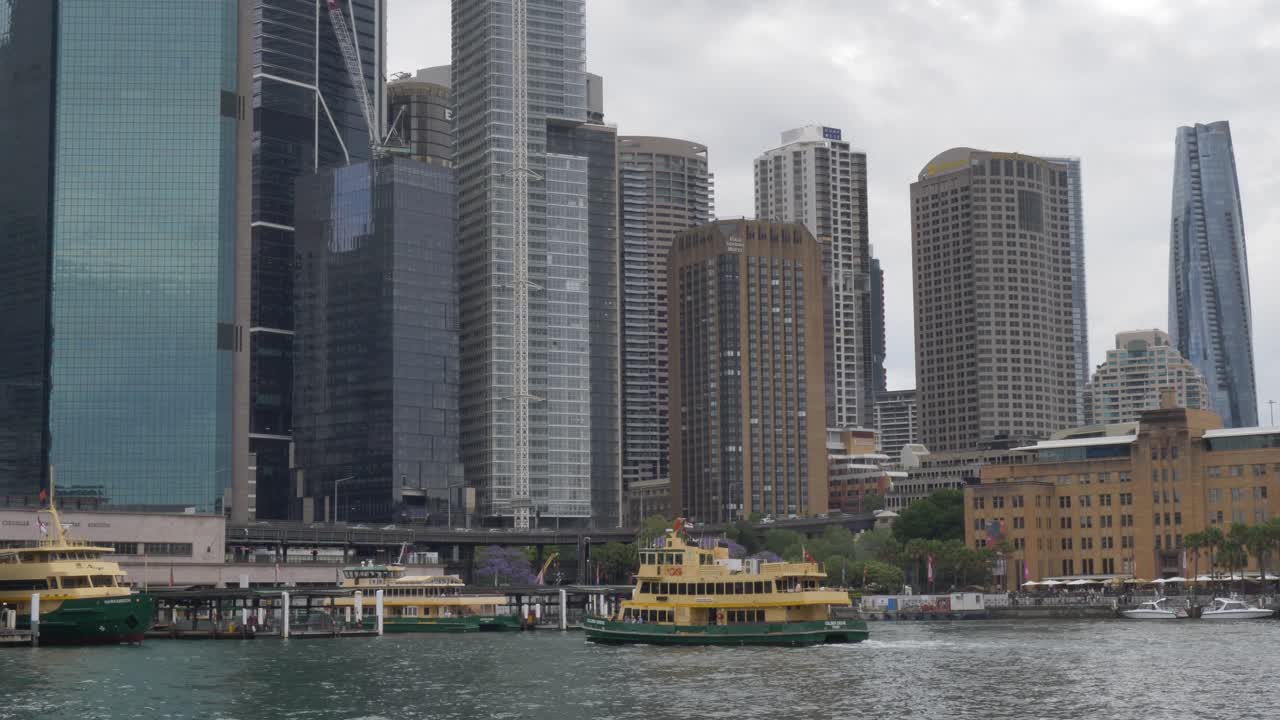 Slow motion landscape of Sydney Harbour ferry ship heading to the dock pier and jetty at Circular Quay foreshore with city buildings and skyline towers in background Australia travel tourism maritime