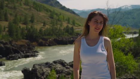 woman in sleeveless shirt on rocky bank of fast creek