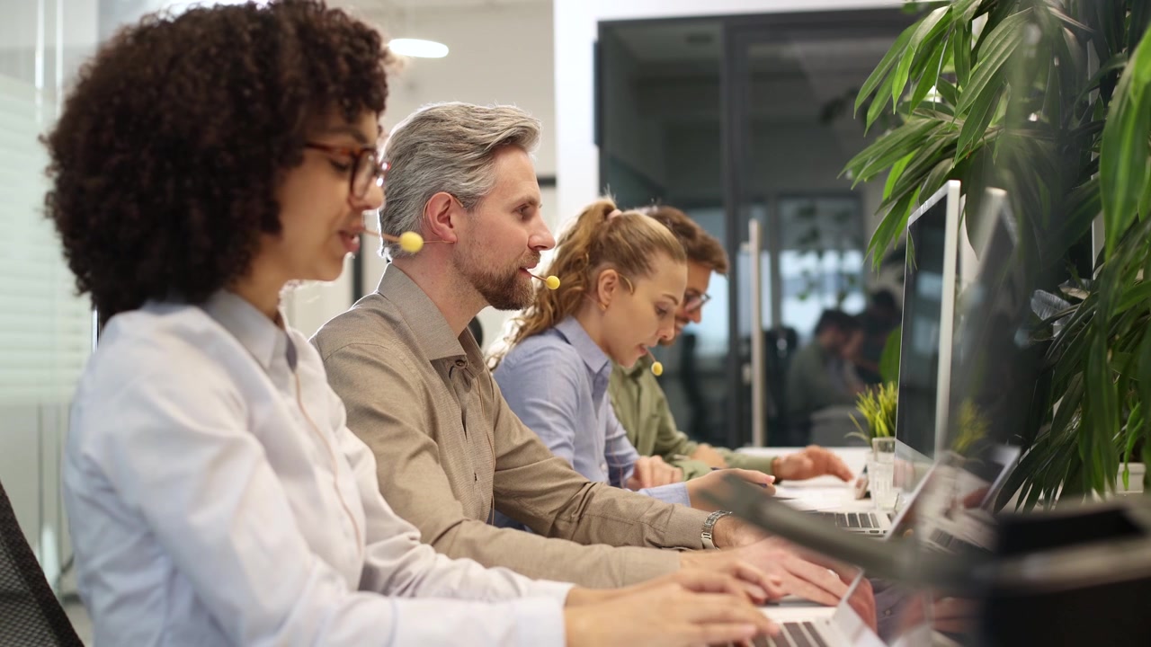 Operatori di call center diversificati che lavorano su portatili in un ufficio moderno