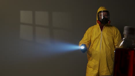 hombre vestido con traje de materiales peligrosos explora una habitación llena de humo