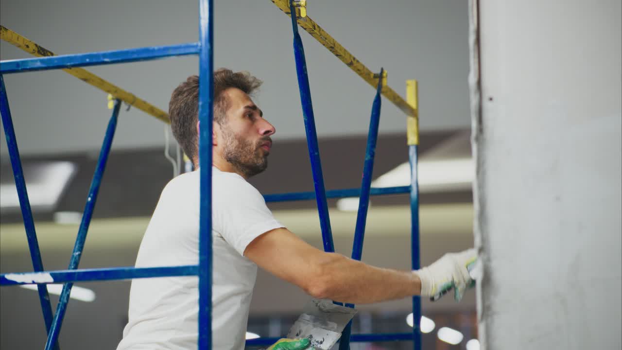 A Skilled Worker Finishing Touches on Wall Decoration While Standing on a Scaffold, Showcasing Craftsmanship in Interior Renovation and Attention to Detail