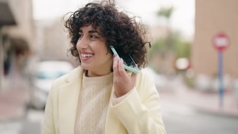 young woman smiling confident listening audio message by the smartphone at street