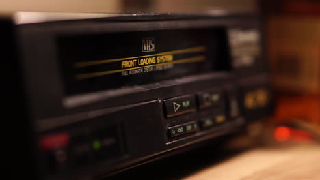 inserting vhs video cassette tape and pressing play button on player, close up