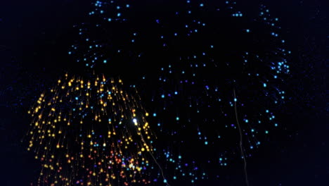 animation of happy new year text in blue with colourful new year fireworks exploding in night sky