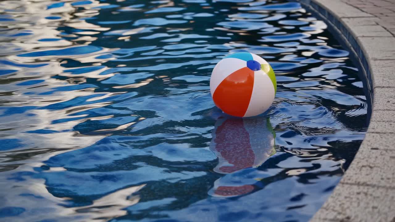 Vibrant beach ball floating serenely on the surface of a tranquil swimming pool, creating gentle ripples in the clear blue water, evokes feelings of summer relaxation and leisure