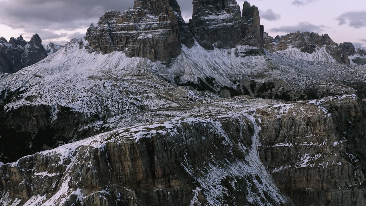 Vista aerea inclinata verso le montagne delle Tre Cime di Lavaredo, serata innevata nelle Dolomiti, Italia.